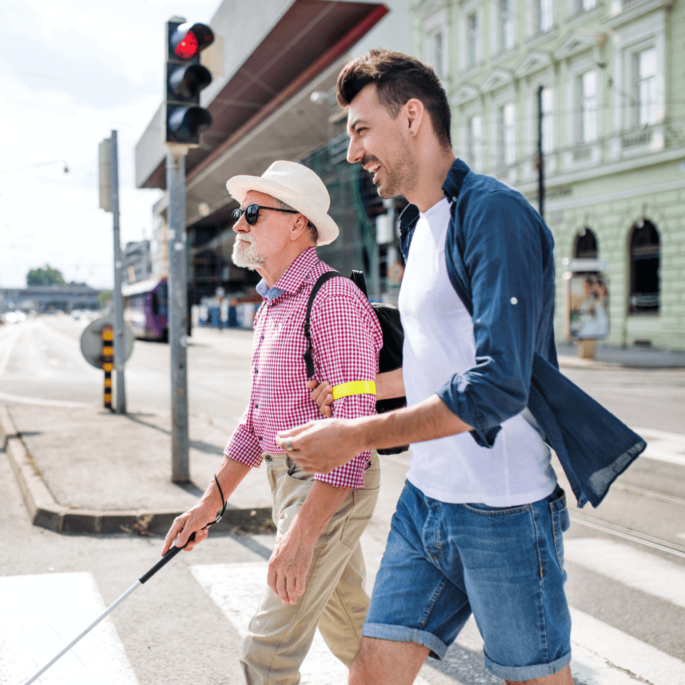 Carer helping blind person to cross the signals