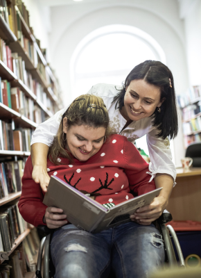 Participant reading book at a library with carer